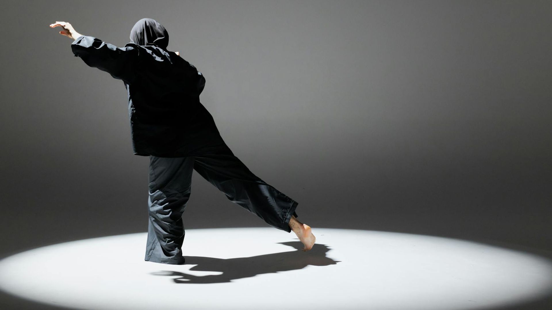 Person performing dynamic cardio movements in dark studio.
